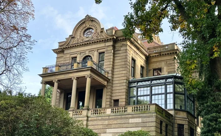 Außenansicht der historischen Thyssenvilla in Mülheim an der Ruhr, mit großzügiger Fassade und klassischer Bauweise, ein Relikt aus der Industriellen Ära.