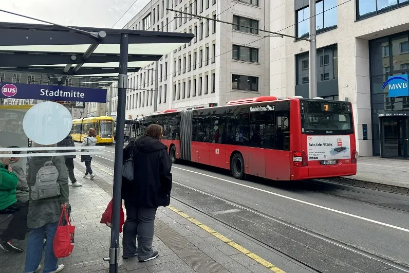 Öffentlicher Nahverkehr in Mülheim - Haltestelle Stadtmitte in Mülheim mit wartenden Fahrgästen und öffentlichen Verkehrsmitteln im Hintergrund.