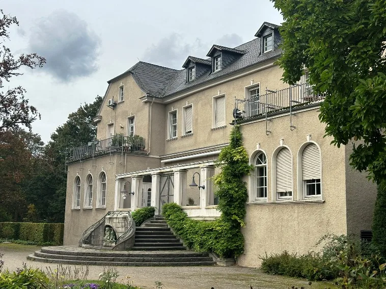 Schloss Styrum in Mülheim an der Ruhr, umgeben von grüner Landschaft und historischen Bäumen.